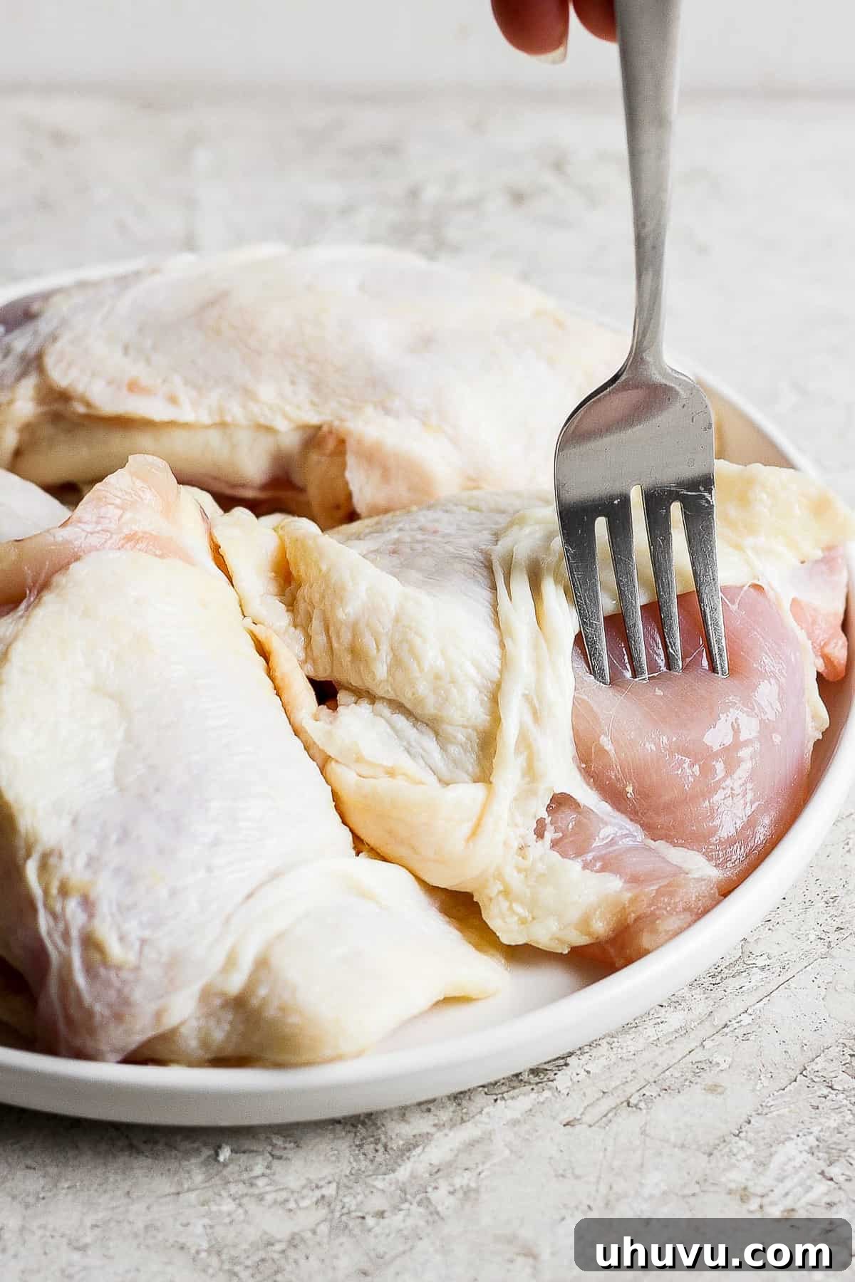Zesty Cilantro Lime Chicken 4 Chicken thighs being gently pricked with a fork to allow the marinade to penetrate deeply into the meat.