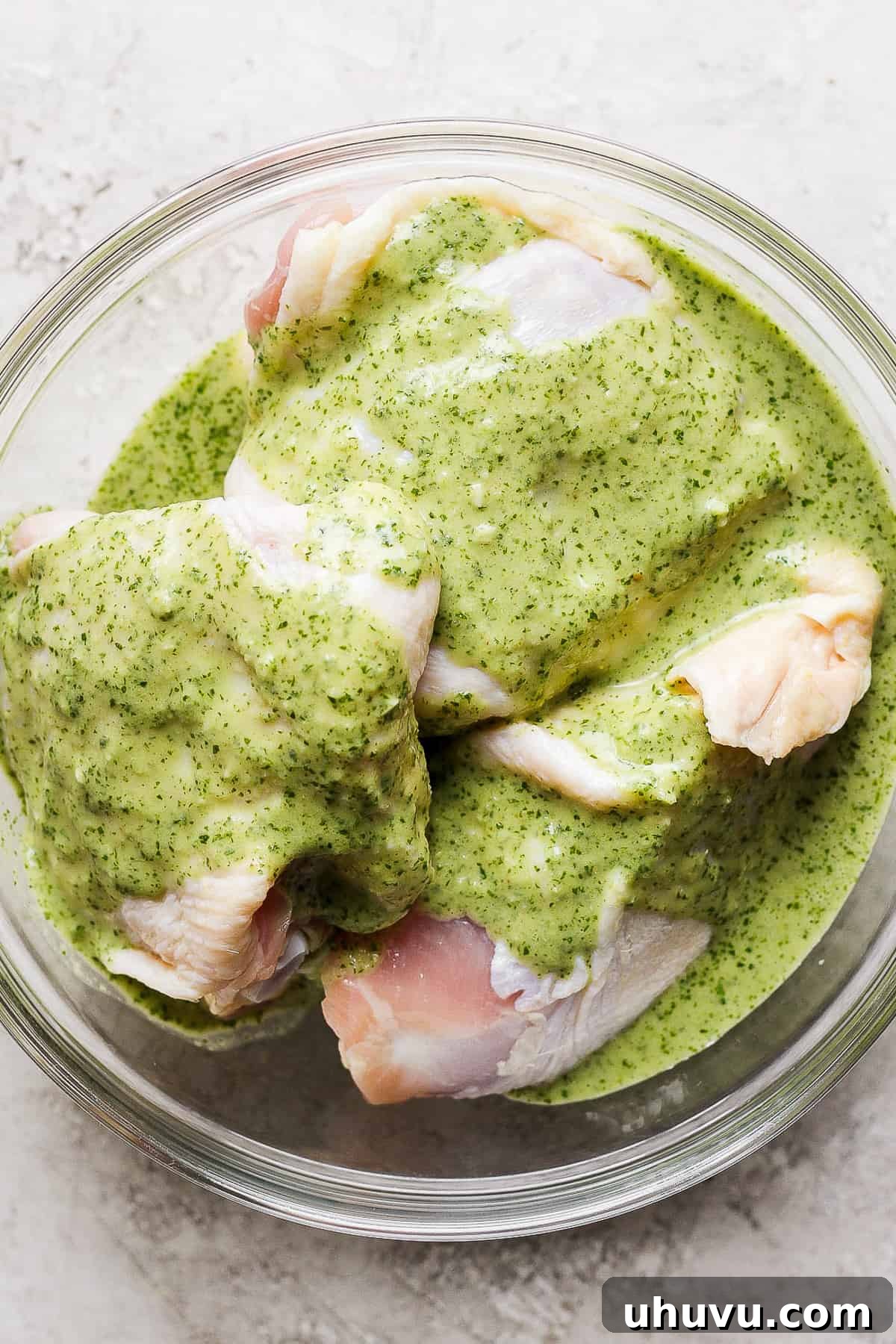 Zesty Cilantro Lime Chicken 7 Chicken thighs submerged in a vibrant green cilantro lime marinade within a bowl, ready to be refrigerated.