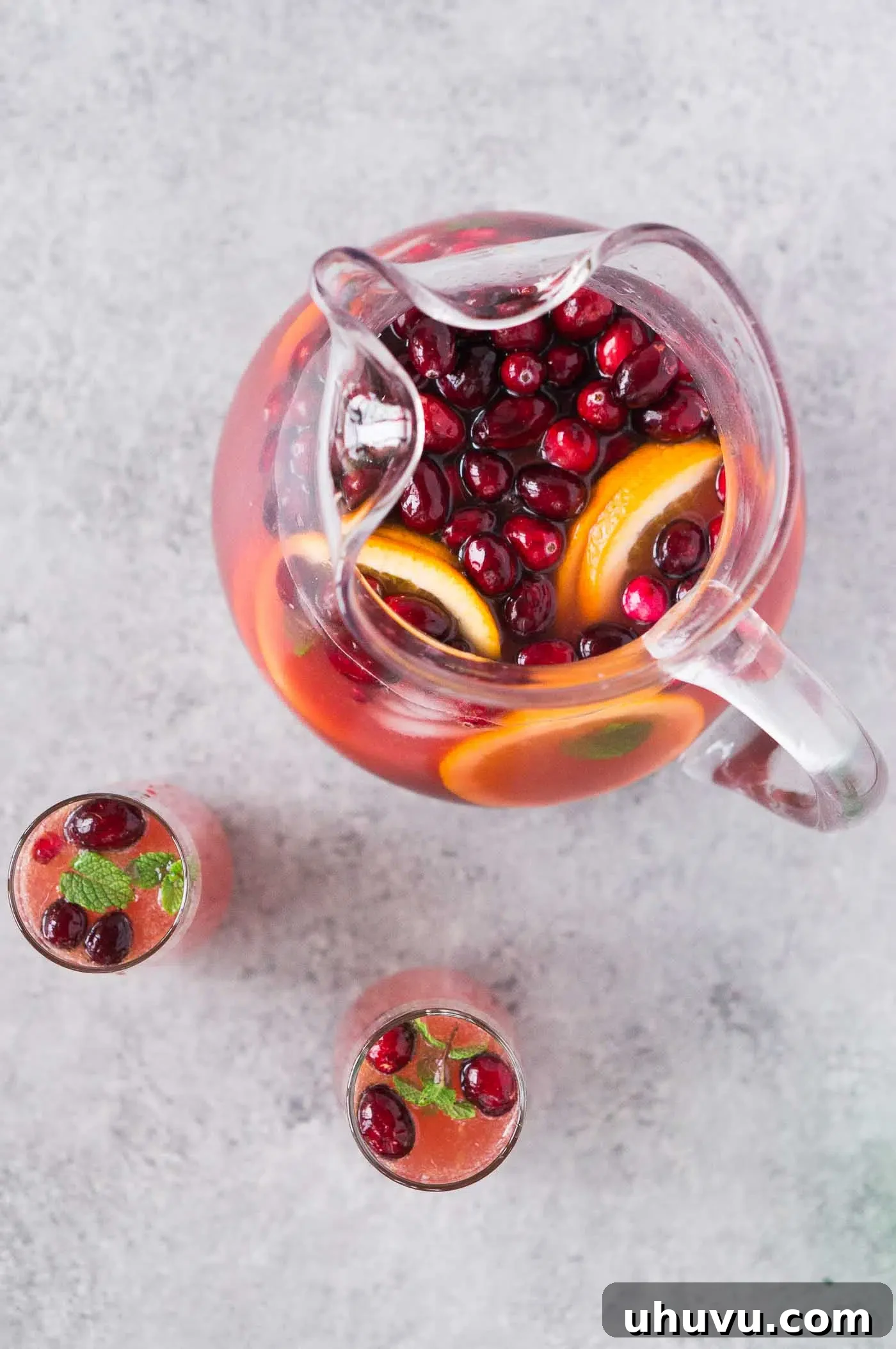 Merry Mixer 5 Overhead view of a pitcher and glasses filled with holiday punch, garnished beautifully