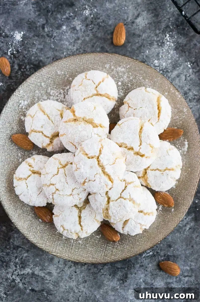 Classic Italian Amaretti 2 Amaretti cookies with fresh lemons and raw almonds, showcasing their golden-brown crackled tops.