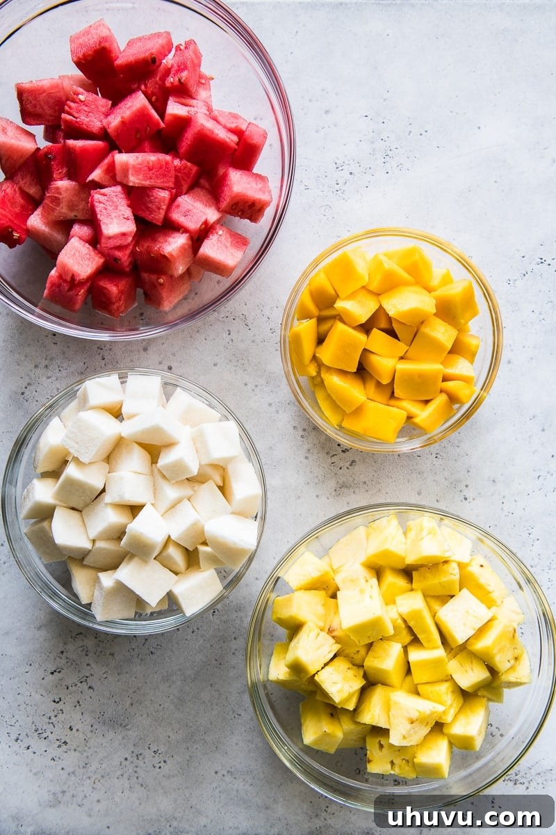 Chili-Lime Fruit Cups 3 Freshly cut fruit in bowls for Mexican Fruit Cups, including vibrant watermelon, sweet mango, crisp jicama, and juicy pineapple.