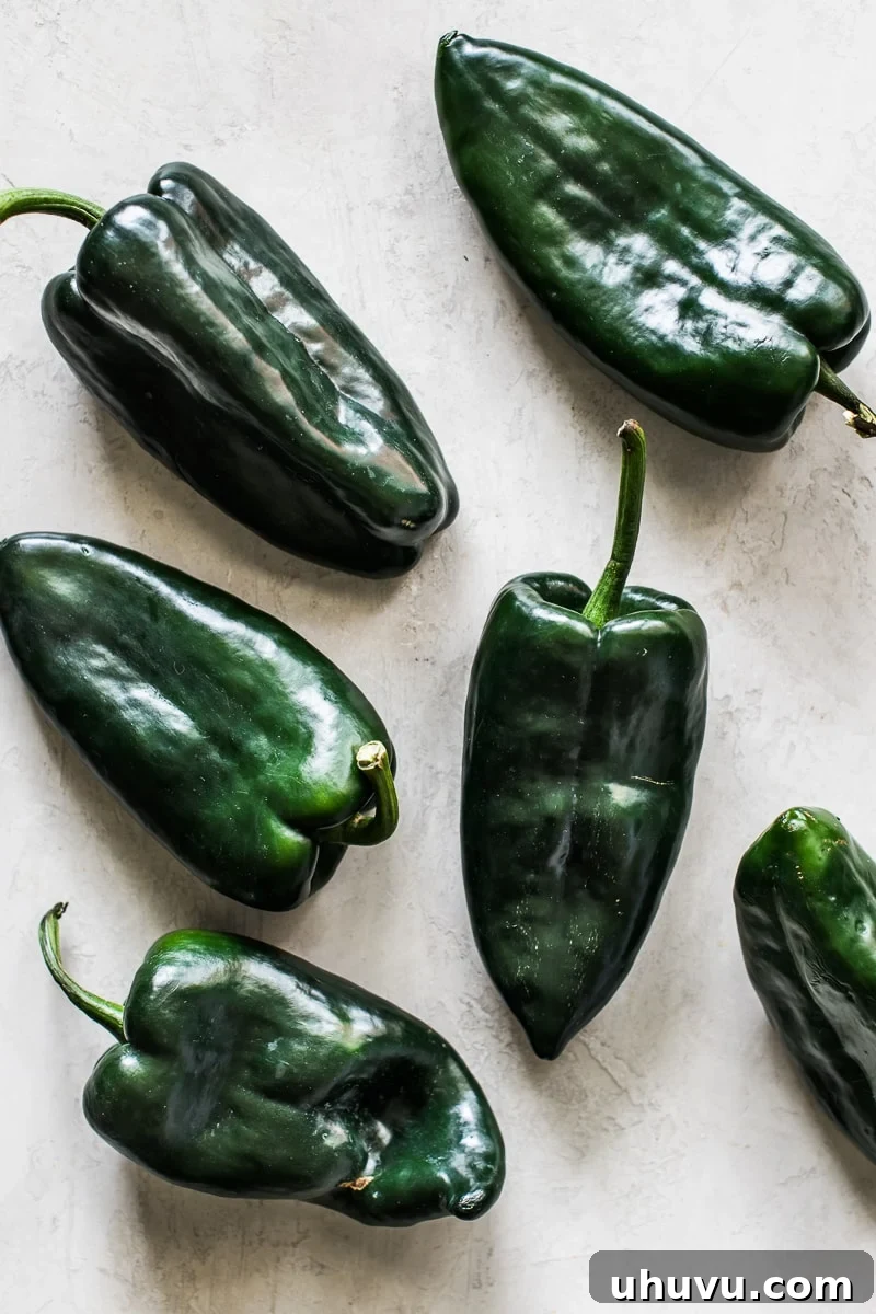 Fresh, raw poblano peppers resting on a kitchen table, ready for roasting.