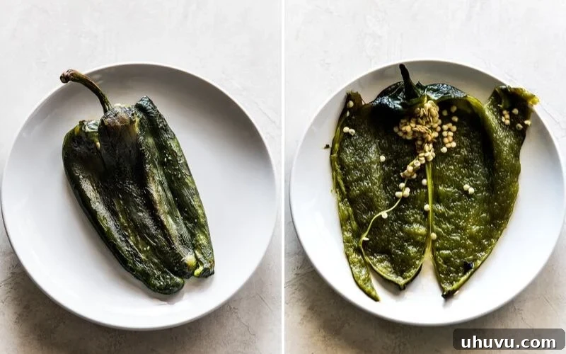 A roasted poblano pepper cut open on a plate, showing the seeds and veins inside.