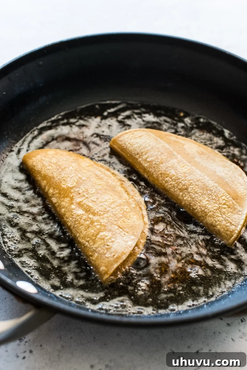 Crispy Golden Potato Tacos 5 Potato Tacos (Tacos de Papa) frying in a large skillet, achieving a golden crisp.