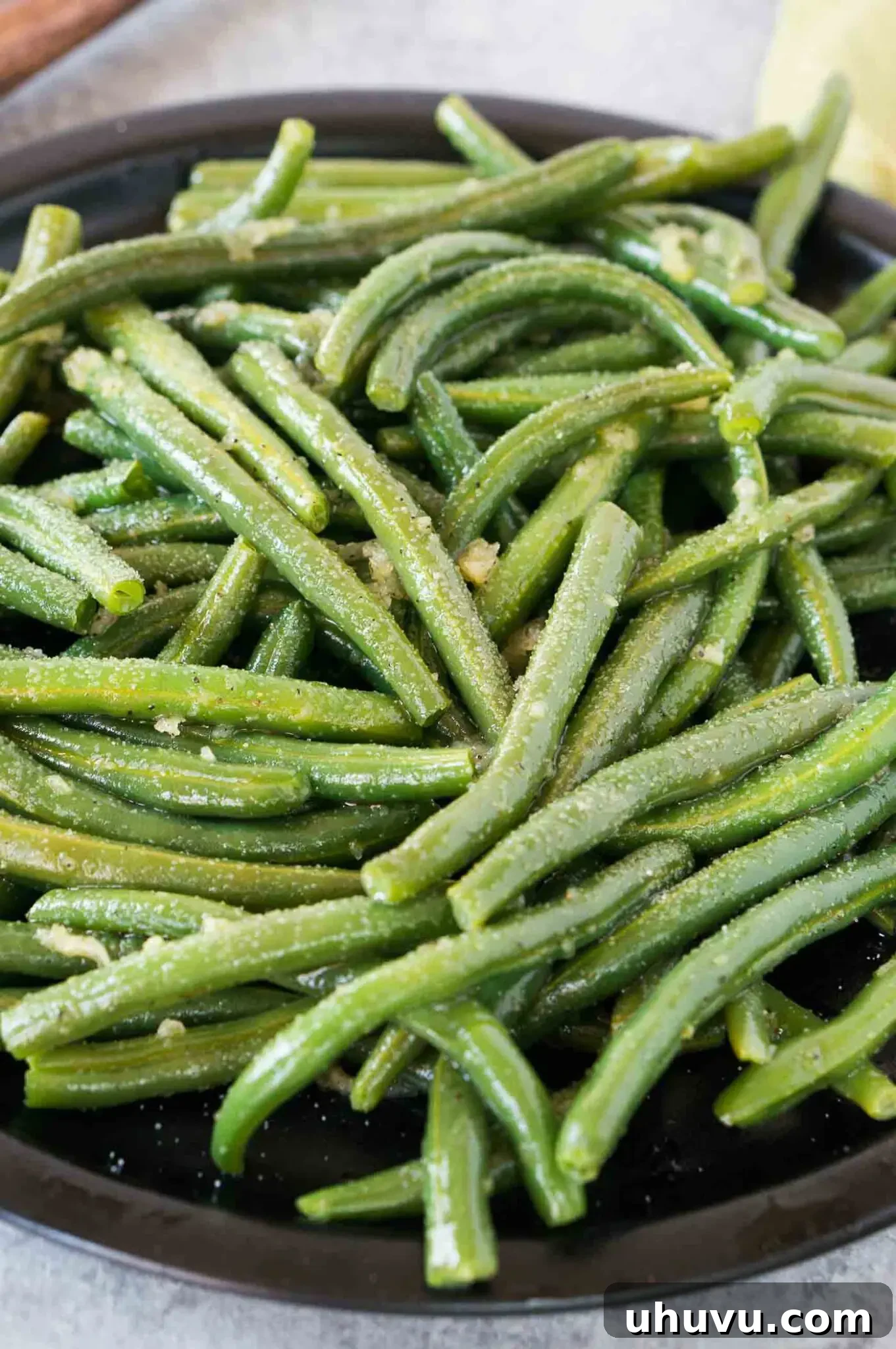 close up image of cooked green beans with seasonings served on a plate