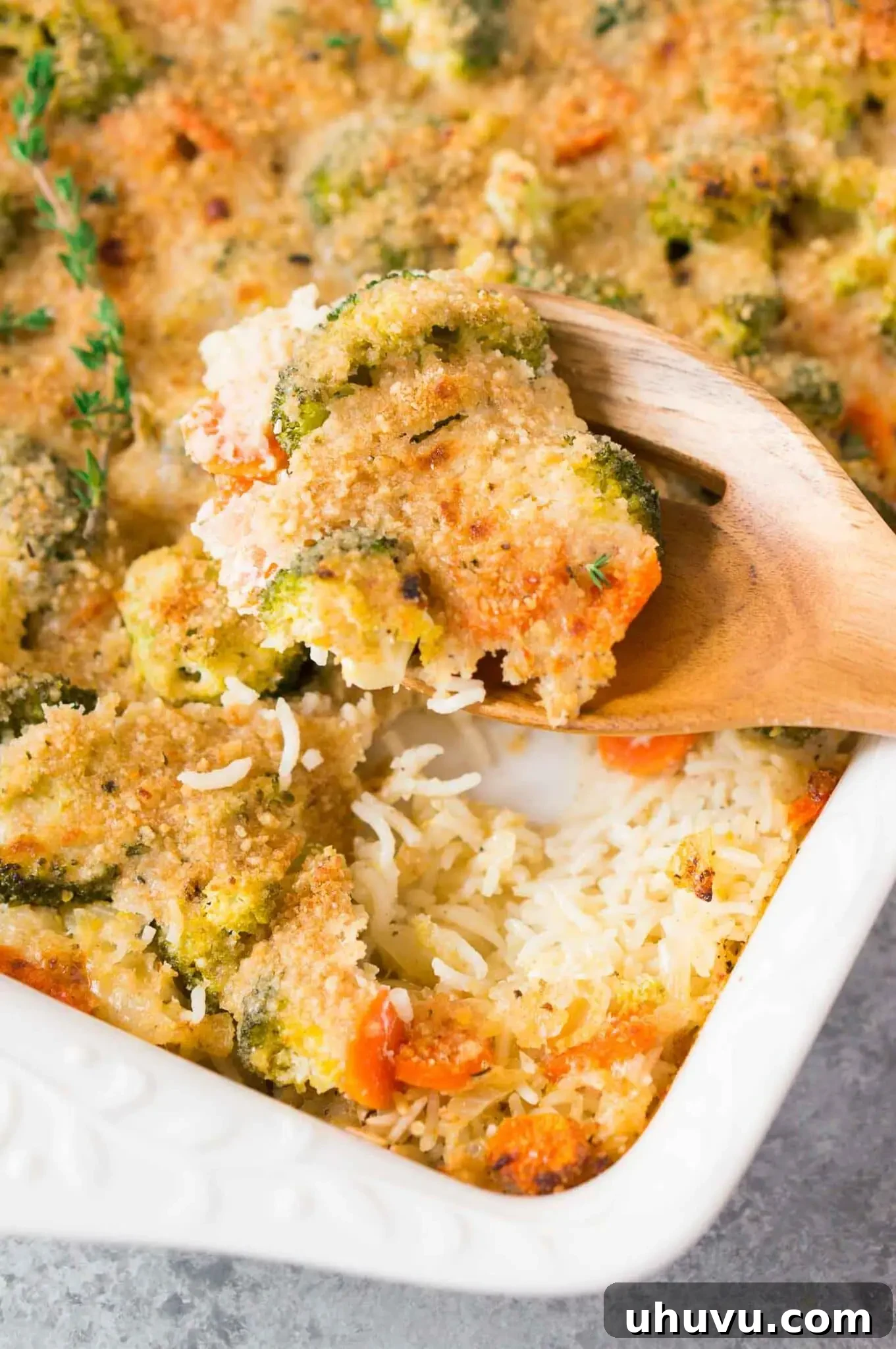A serving spoon lifting a portion of the cheesy broccoli and rice casserole, showing the creamy texture and tender vegetables