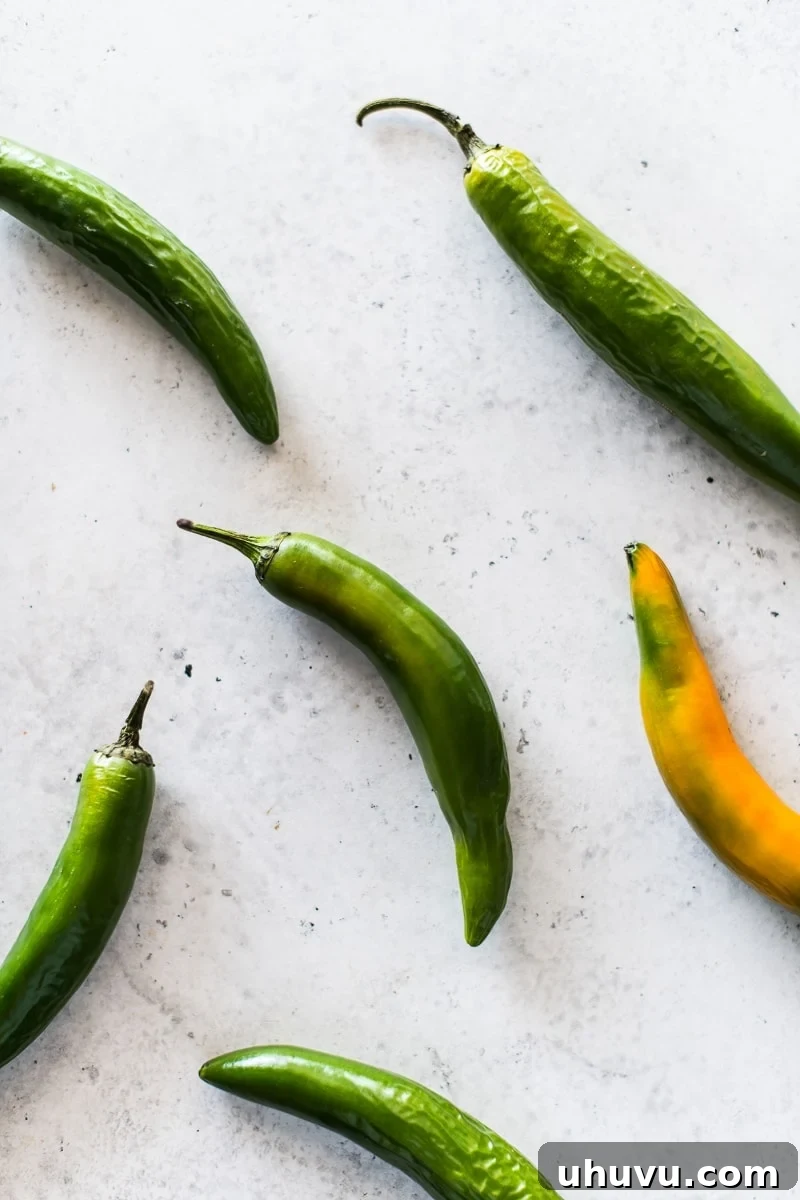 Decoding Serrano Peppers 2 Fresh green Serrano peppers neatly arranged on a clean white surface, showcasing their slender form and rich color, ready for culinary use.