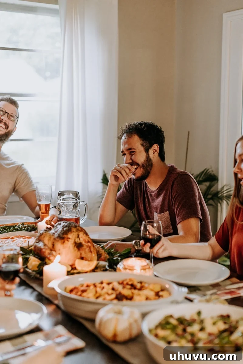 Friendsgiving Fun: Tips, Tricks, and Treats 3 Friends laughing and enjoying a beautifully set dining table laden with Thanksgiving food during a Friendsgiving celebration.
