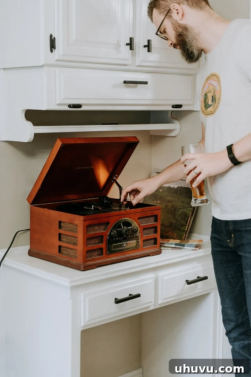 Friendsgiving Fun: Tips, Tricks, and Treats 7 A man carefully placing a record on a turntable, setting the musical mood for a Friendsgiving party.