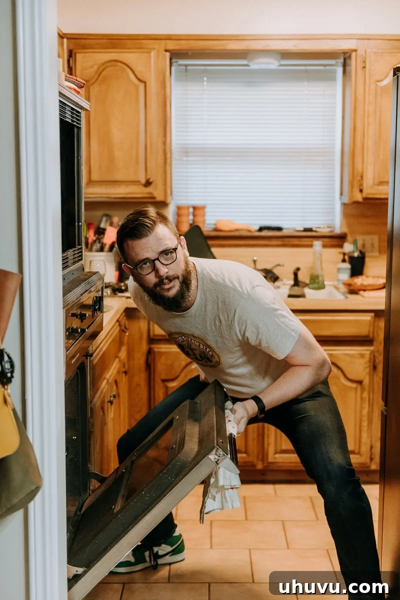 Friendsgiving Fun: Tips, Tricks, and Treats 8 A man comically posing in front of an oven, ready to retrieve a Thanksgiving turkey.