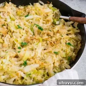 Sauteed cabbage in a white skillet, garnished with fresh parsley.