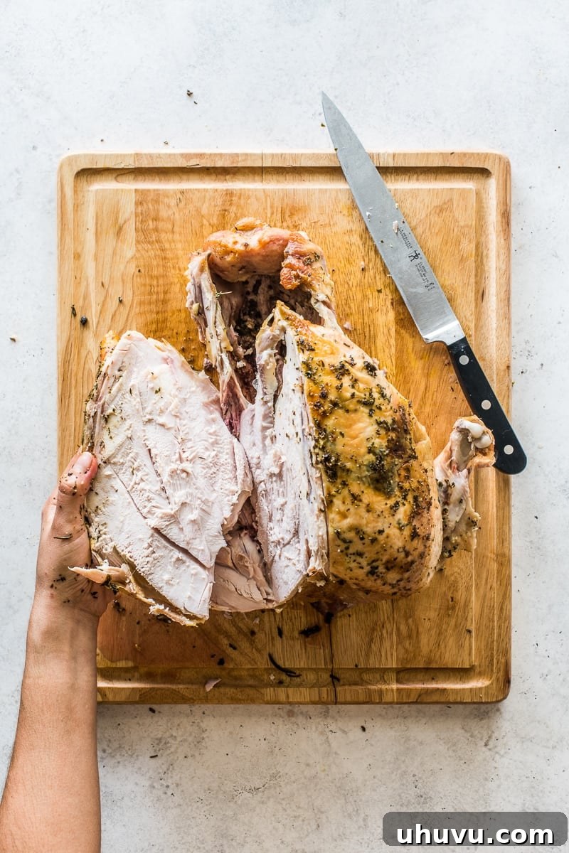 Precisely carving a succulent breast off a roasted turkey, demonstrating the crucial angled cut along the breastbone to maximize meat retrieval.