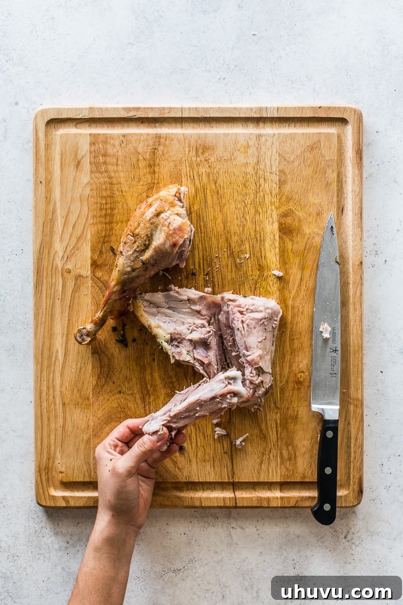 Detailed demonstration of removing the thigh bone from a roasted turkey thigh, meticulously revealing tender, boneless dark meat ready for slicing.