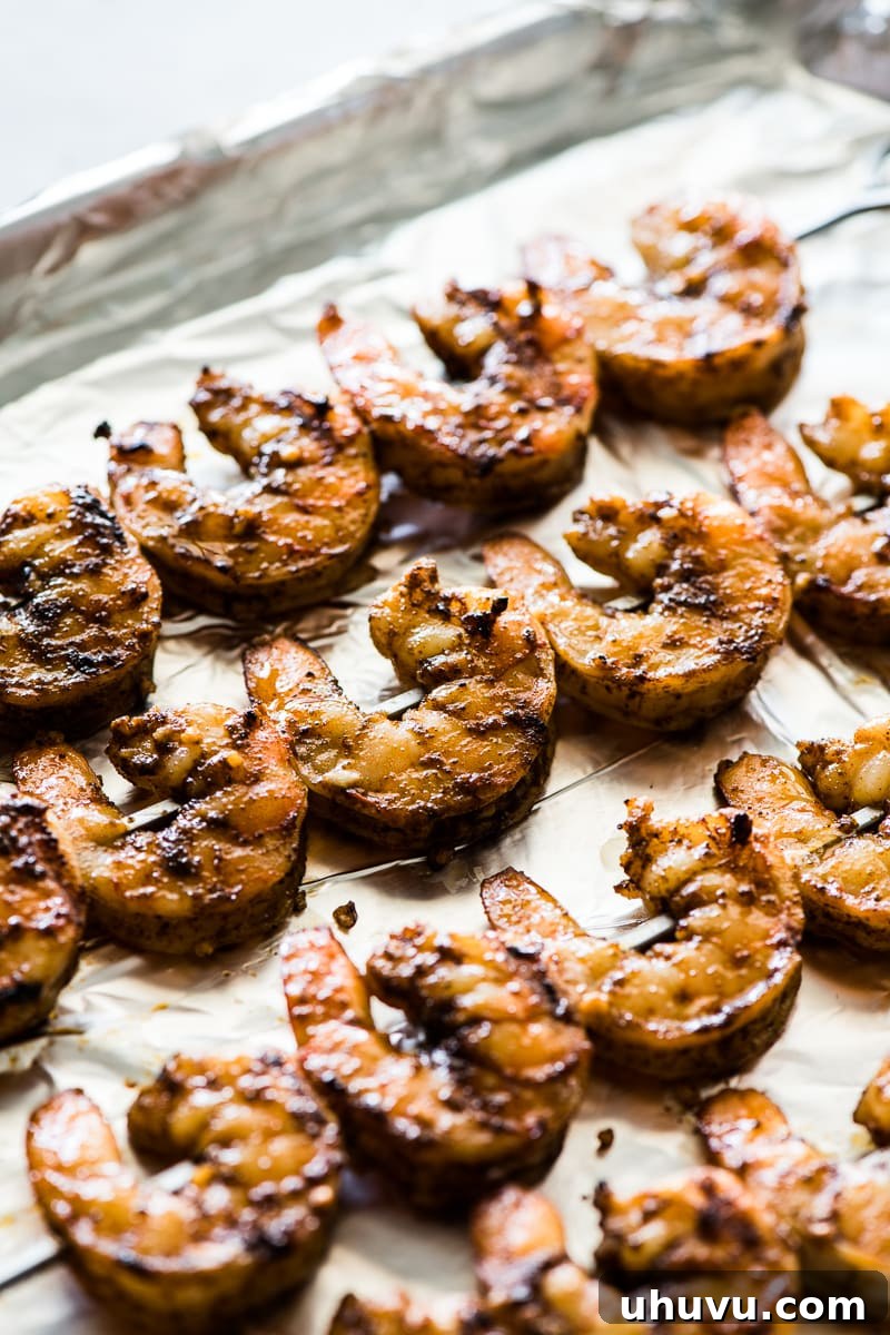 Spicy Grilled Shrimp Tacos with Avocado Crema Slaw 6 Perfectly grilled shrimp skewers arranged on a baking sheet, showcasing their rosy color and ready to be removed for taco assembly.