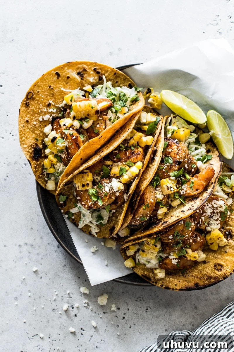 Spicy Grilled Shrimp Tacos with Avocado Crema Slaw 8 Two beautifully assembled grilled shrimp tacos, garnished with cotija cheese and fresh cilantro, resting on a white plate.