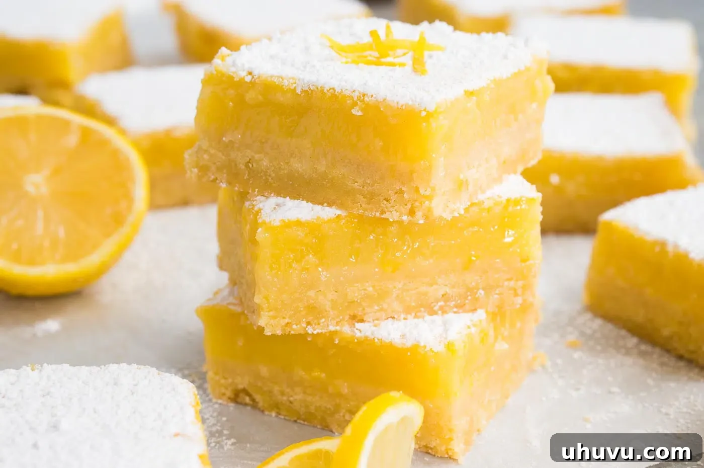 Close-up of freshly baked lemon bars, stacked on a wooden board