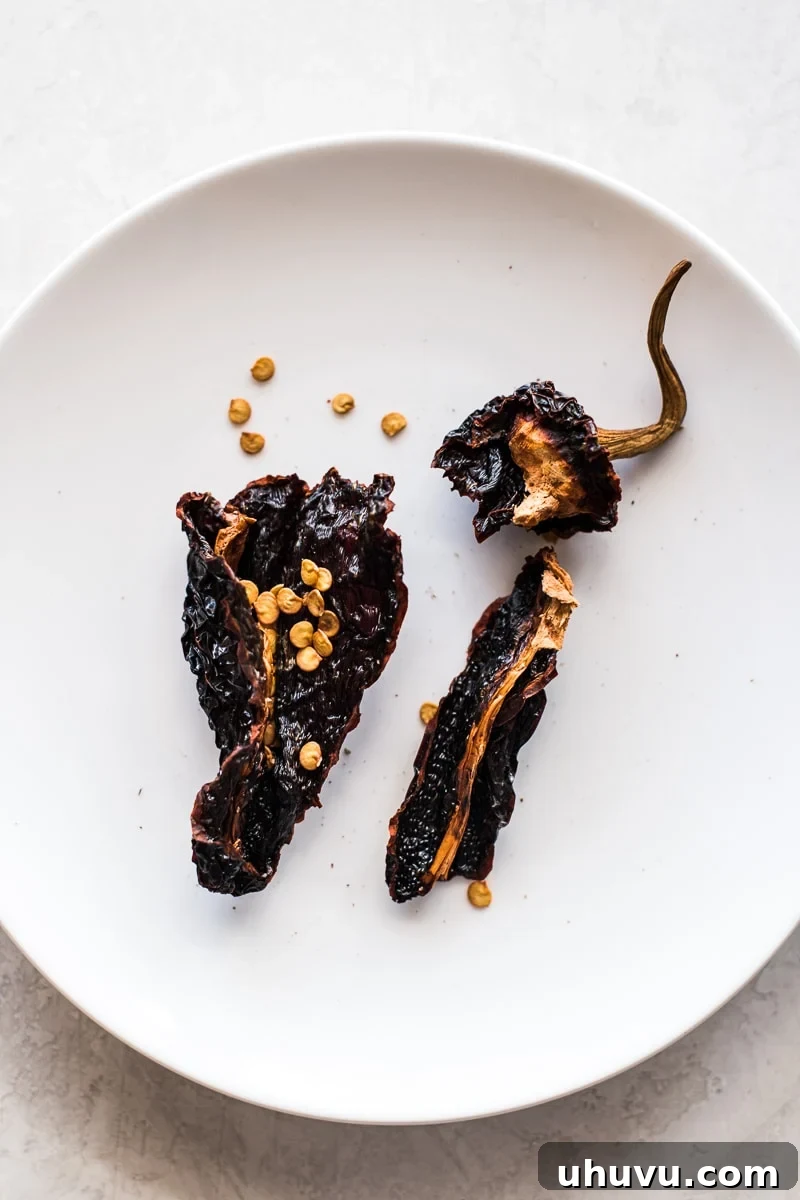 Smoky Sweet Anchos 4 A close-up view of an ancho chile cut open, revealing its interior with seeds and veins exposed, illustrating the preparation process.