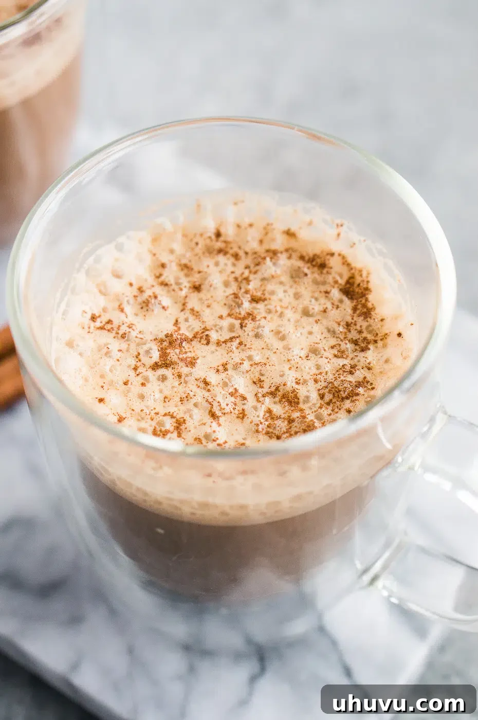 Bulletproof coffee with coconut oil served in a clear glass cup, highlighting its creamy texture