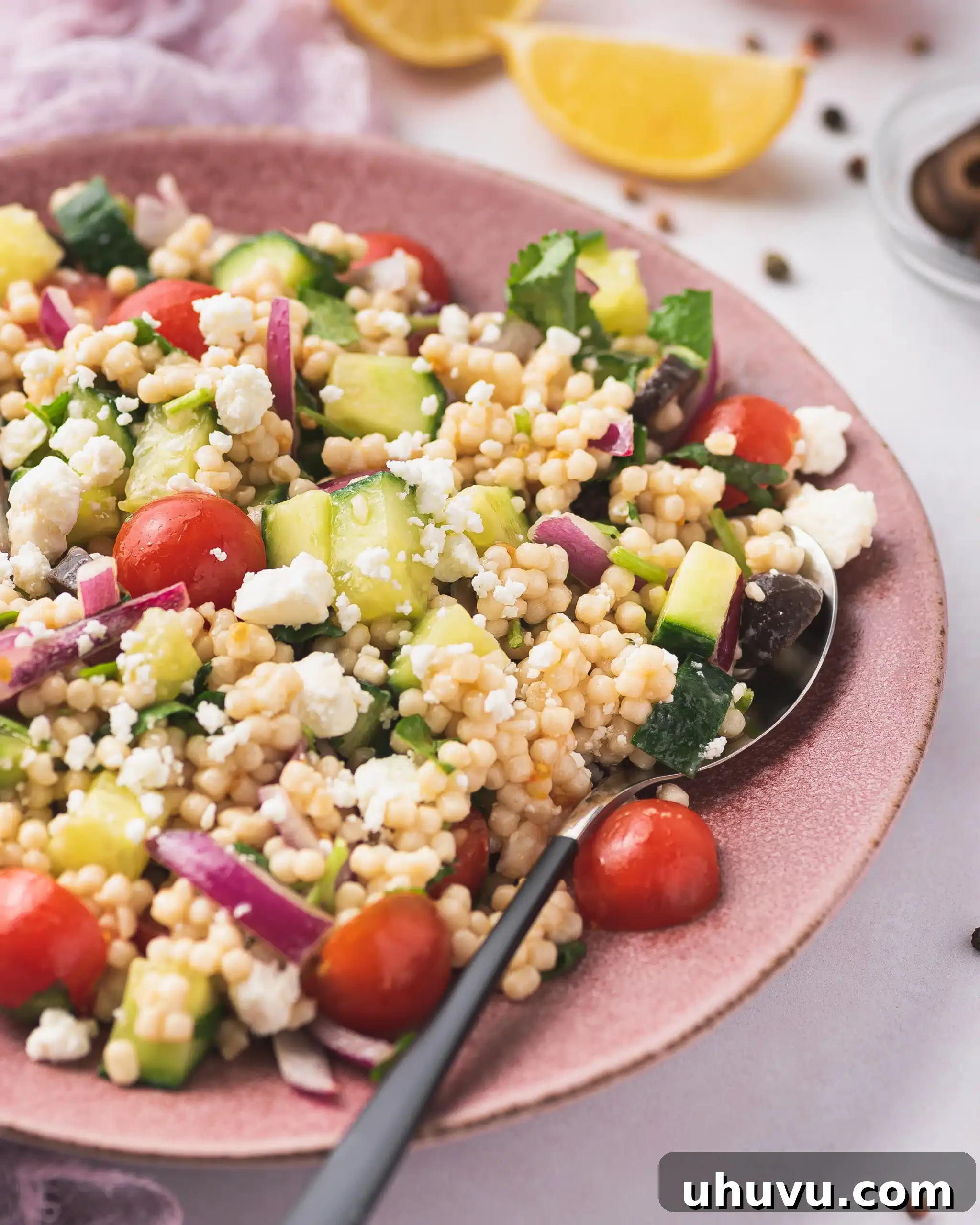 Close up shot of a colorful Mediterranean couscous salad showing off the fresh vegetables and feta cheese