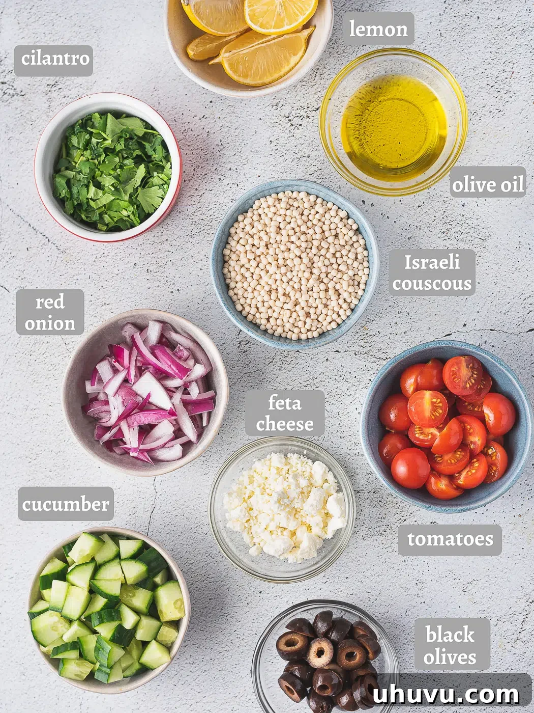 A flat lay image displaying all the fresh ingredients for Mediterranean couscous salad on a wooden board