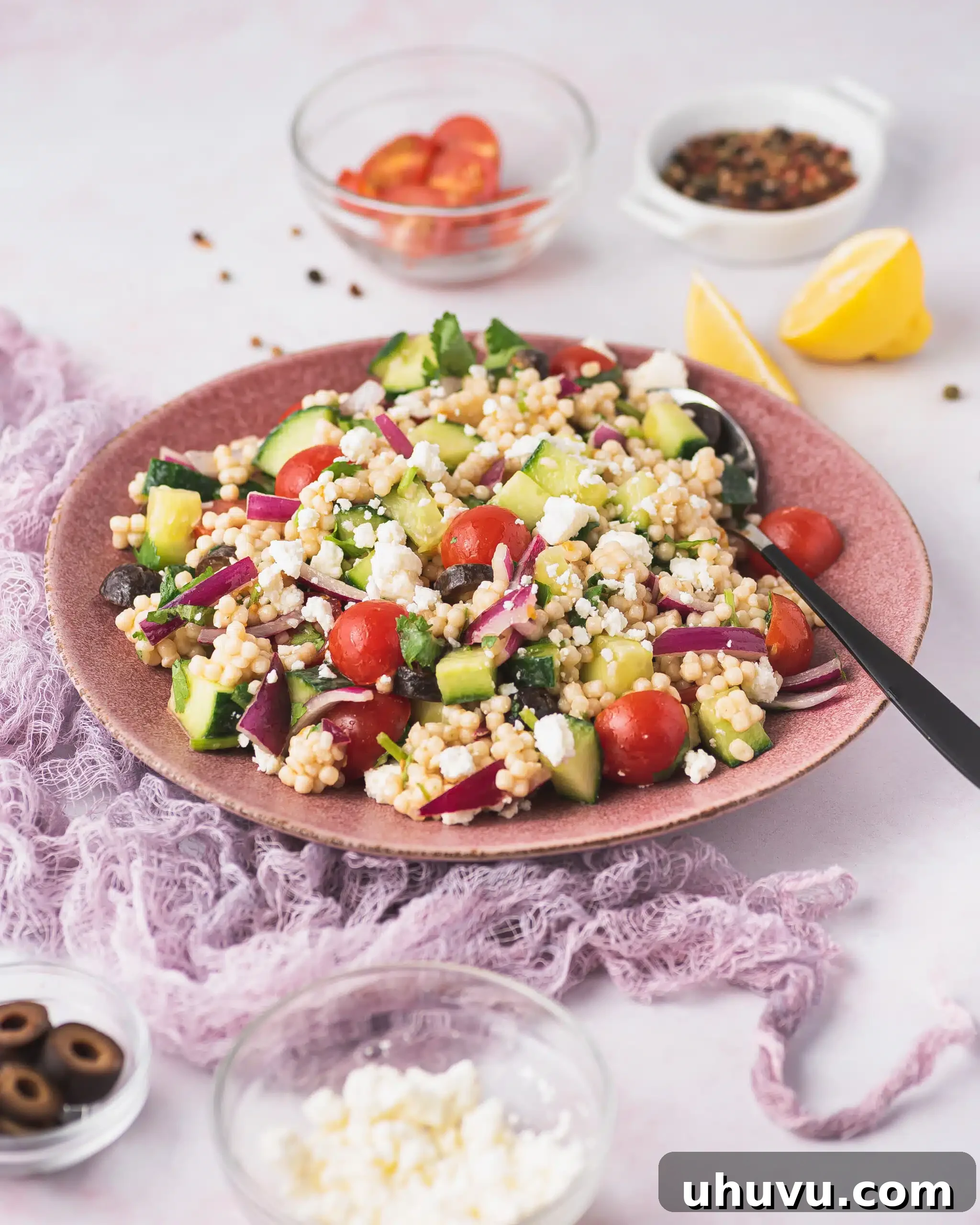 A close-up of a serving of pearl couscous salad with vegetables on a plate, ready to be eaten