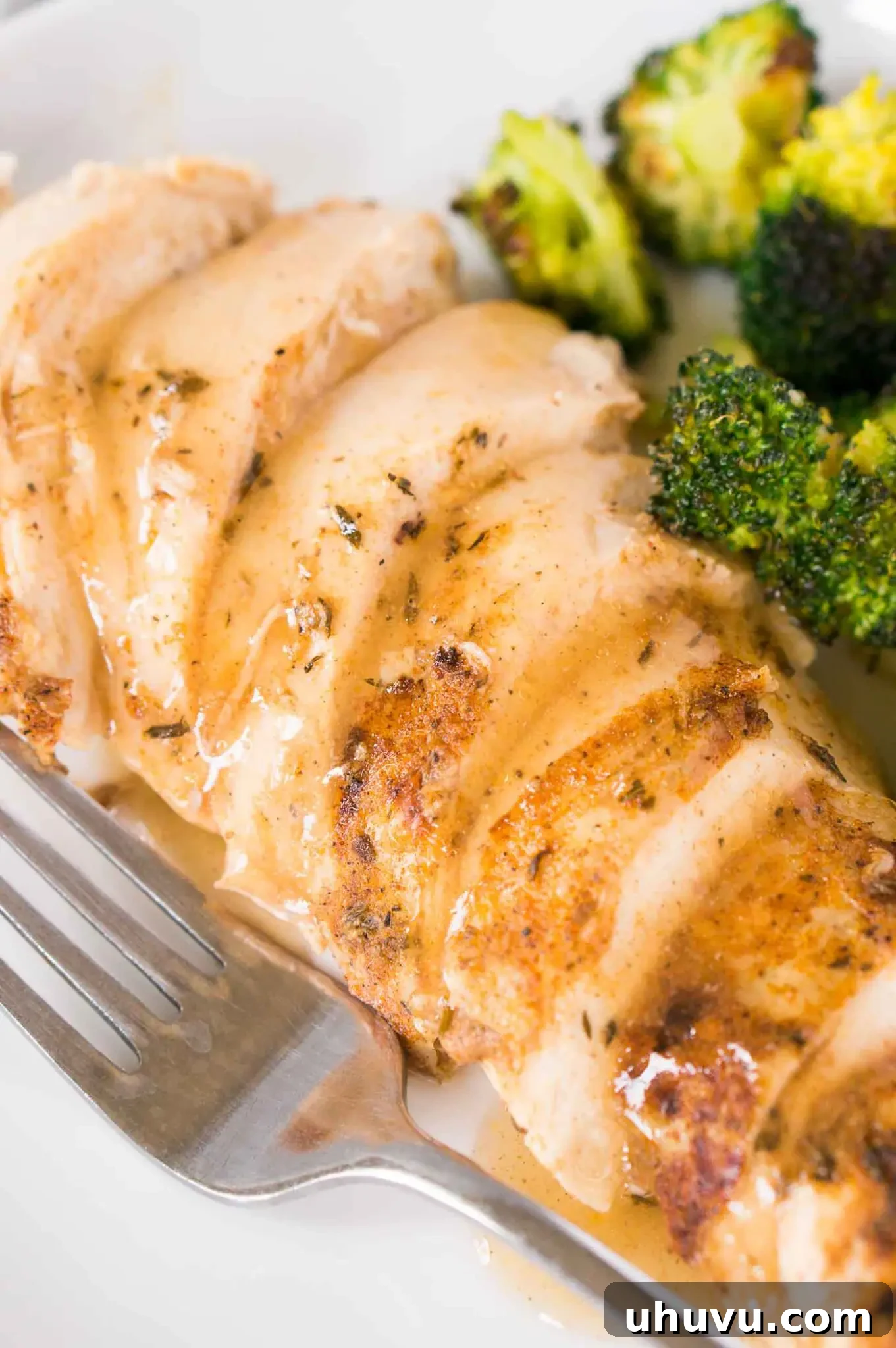 close up image of sliced chicken breast and gravy on a plate with broccoli