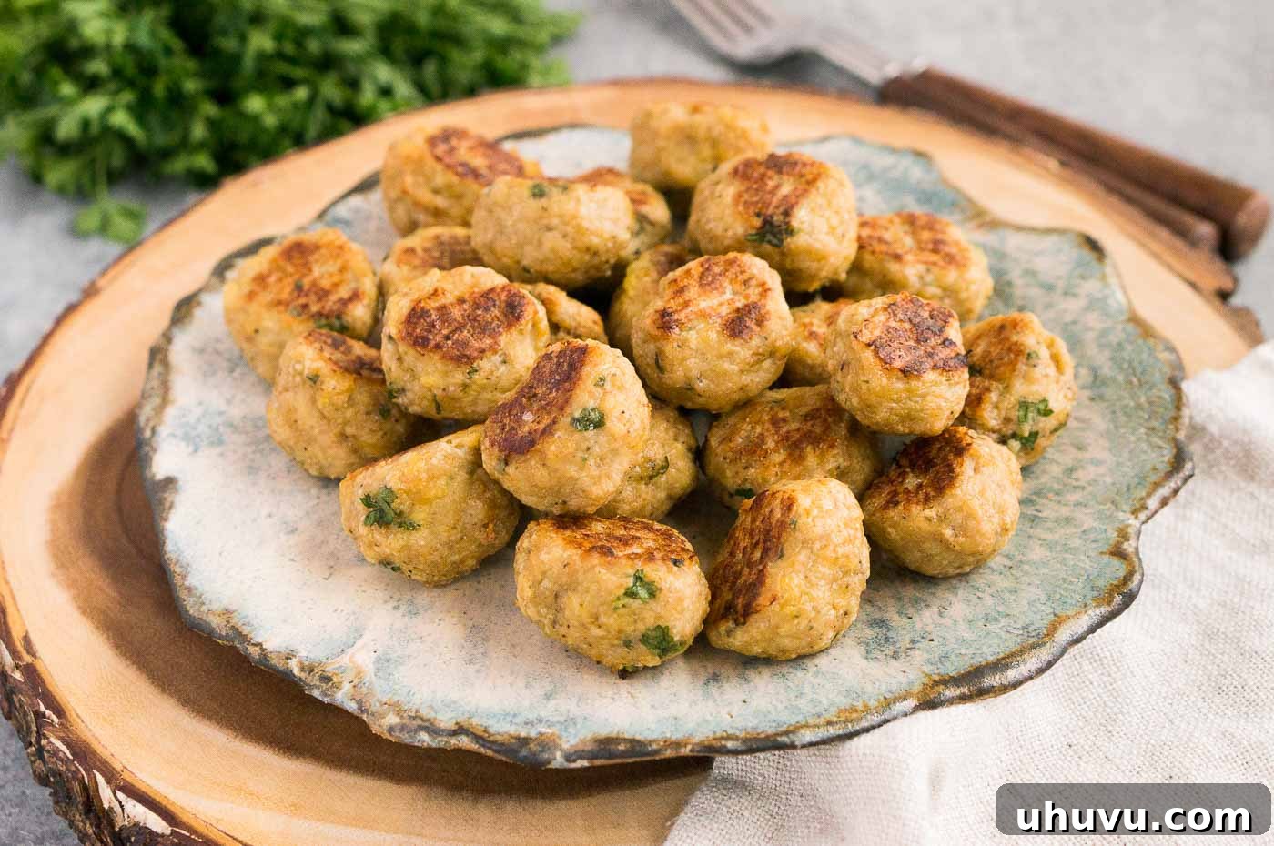 Savory Chicken Meatballs 3 baked chicken meatballs on a plate with fresh herbs
