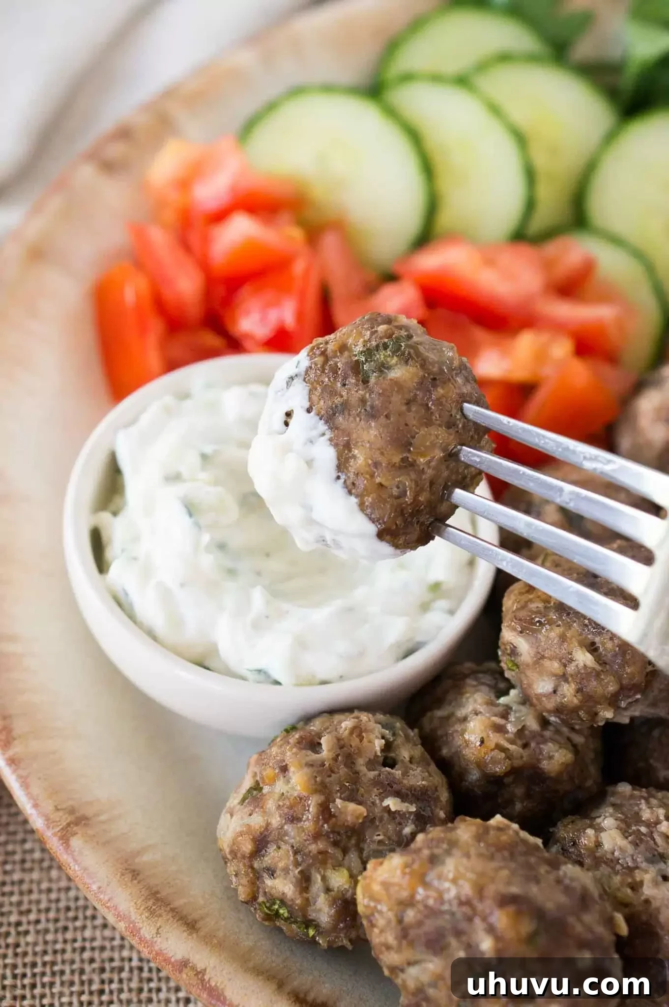 dipping keftedes in tzatziki sauce