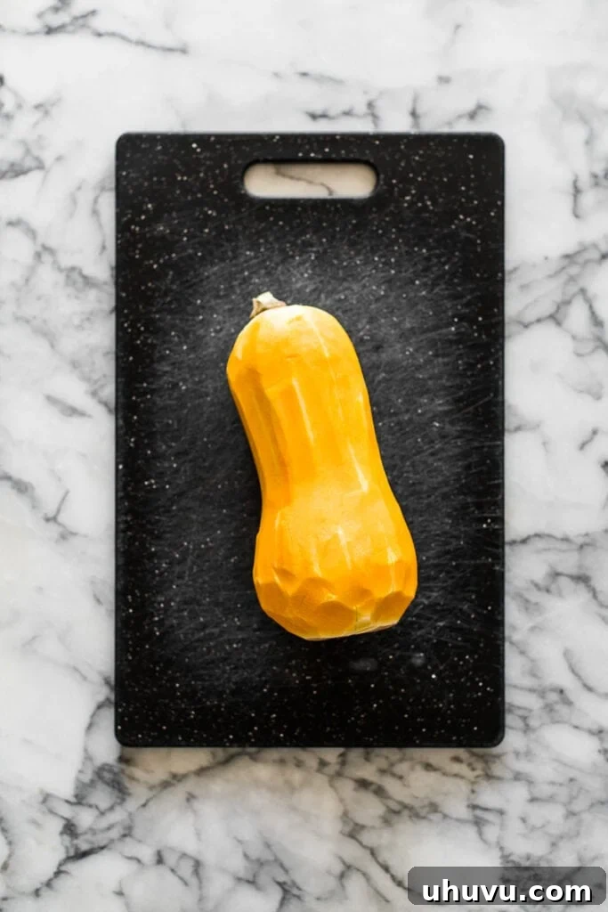 A peeled butternut squash on a cutting board, ready for slicing.