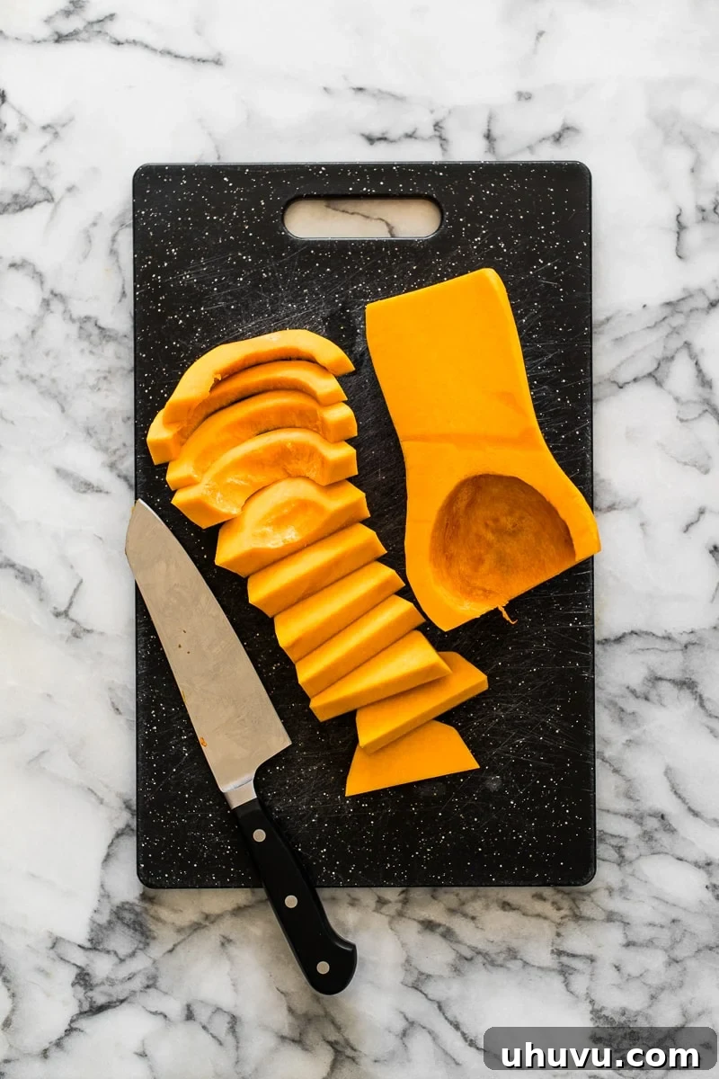 Sliced butternut squash in half-moon shapes arranged on a cutting board.