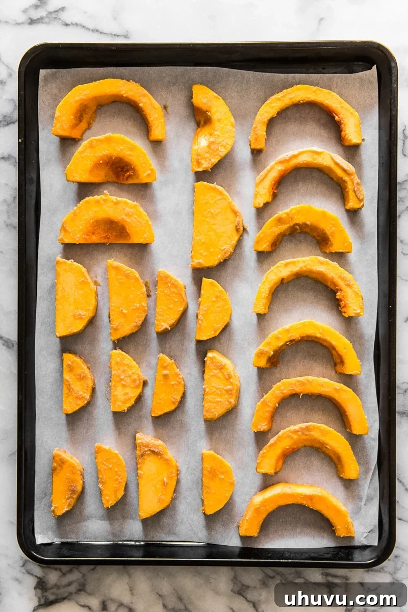 Cut butternut squash cubes on a baking sheet lined with parchment paper, ready for roasting.