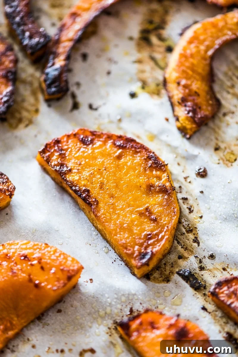 Perfectly roasted butternut squash slices arranged on parchment paper after baking.