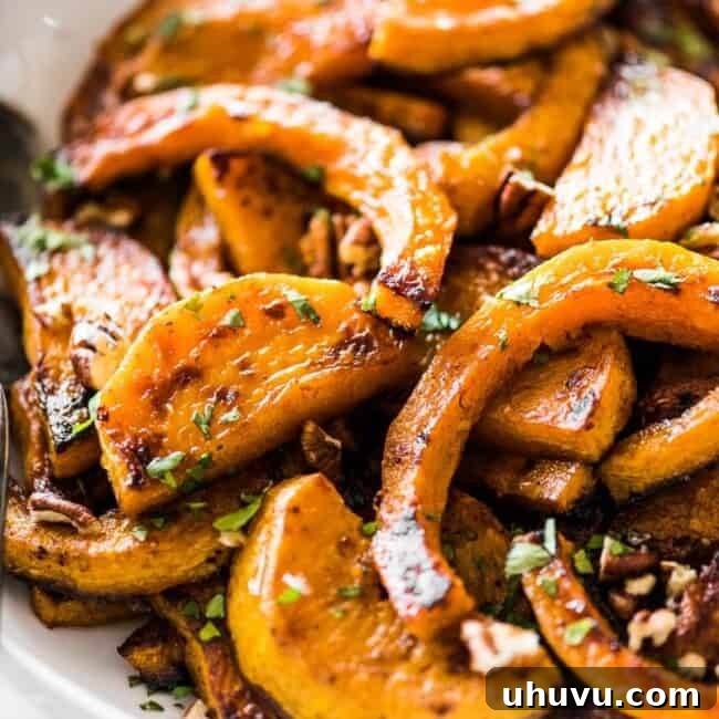 Roasted butternut squash in a bowl, ready to serve, garnished with pecans and cilantro.
