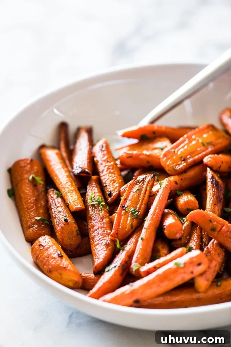Glazed Maple Cinnamon Carrots 5 Close-up of golden-brown oven roasted carrots, glistening with maple syrup and cinnamon glaze.