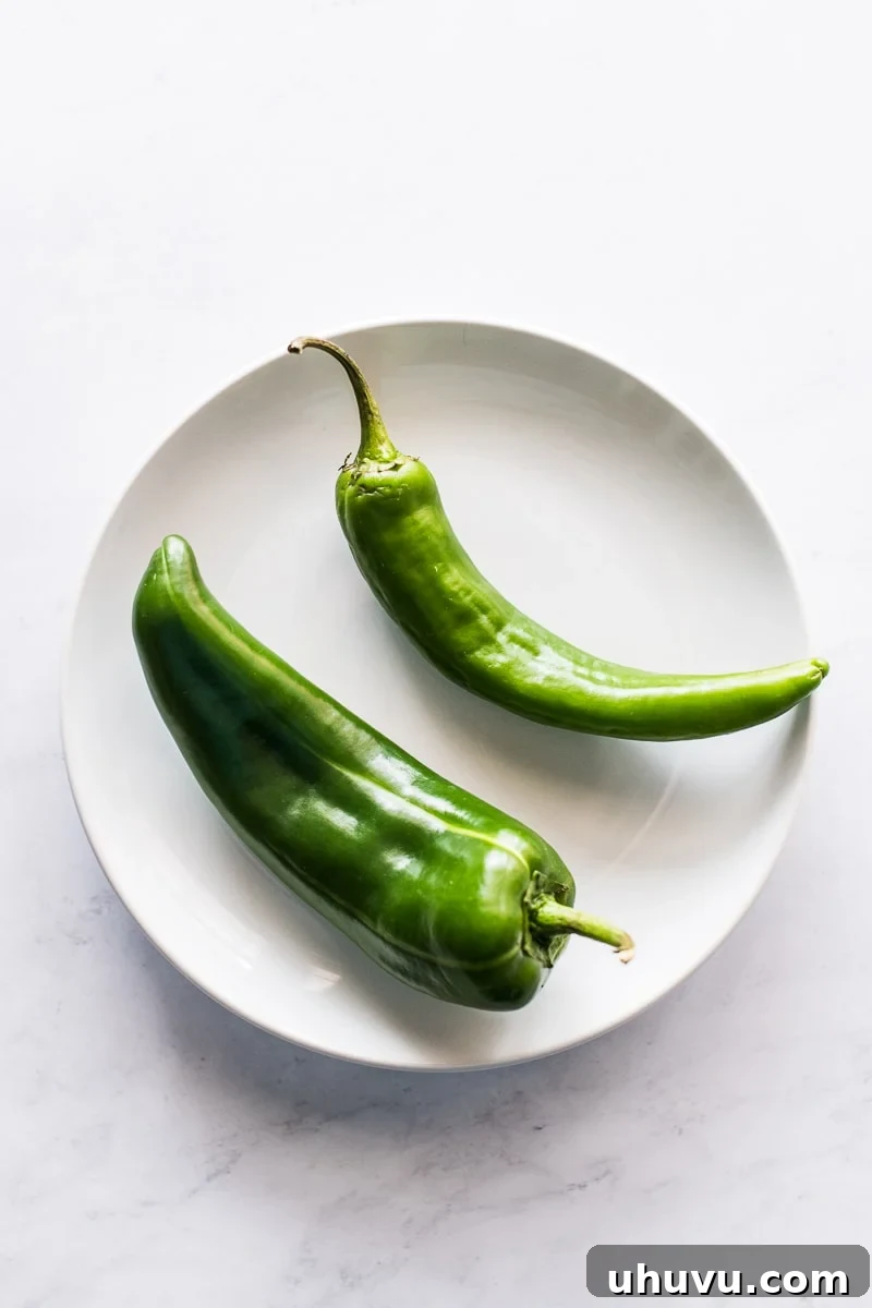 Anaheim Peppers Mild Heat Big Flavor 3 Fresh Anaheim chili peppers arranged artfully on a plate, ready for cooking.
