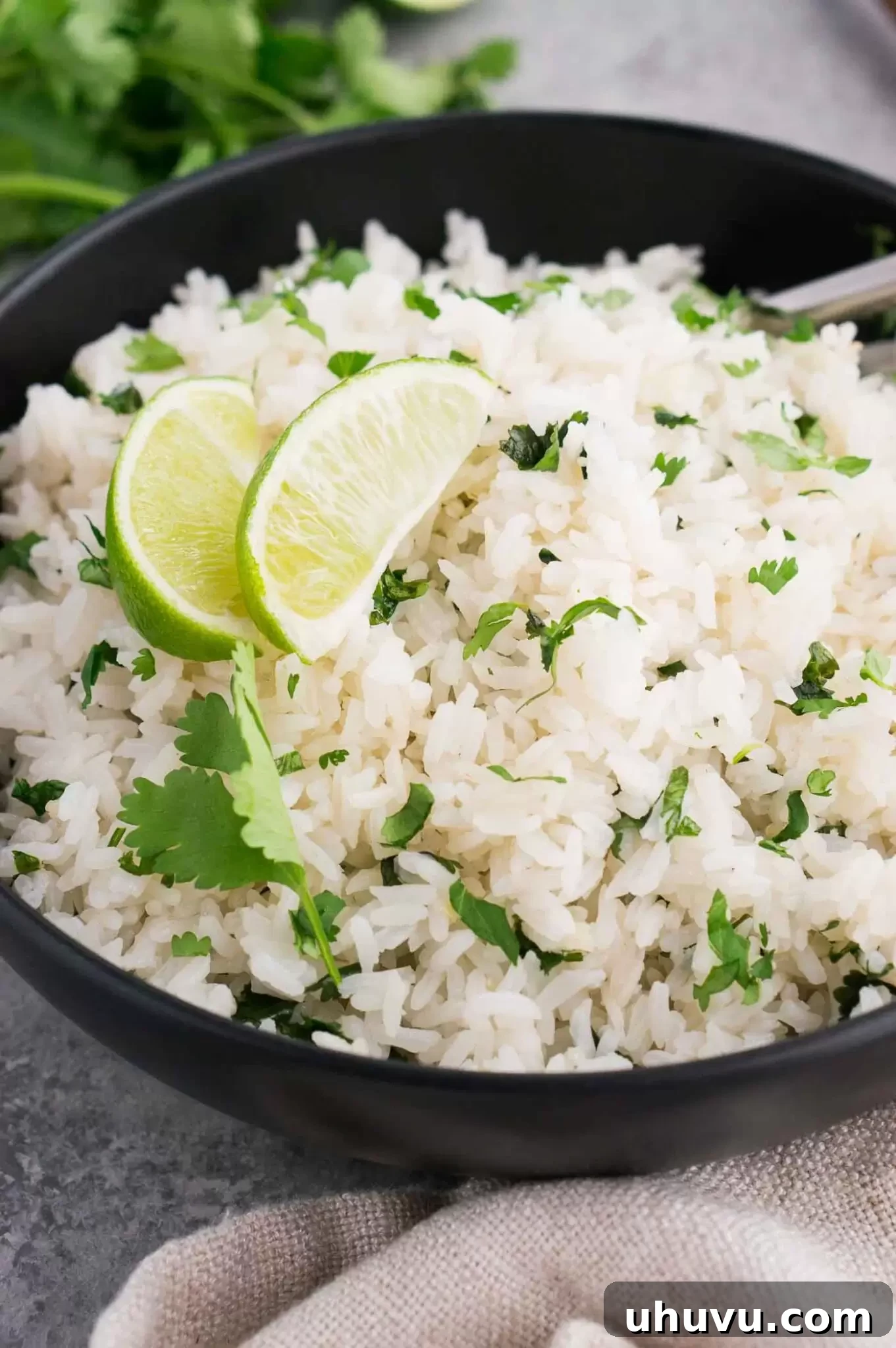 A vibrant close-up shot of fluffy cilantro lime rice, featuring individual grains, green specks of cilantro, and subtle yellow flecks of lime zest, appealingly presented in a serving bowl.