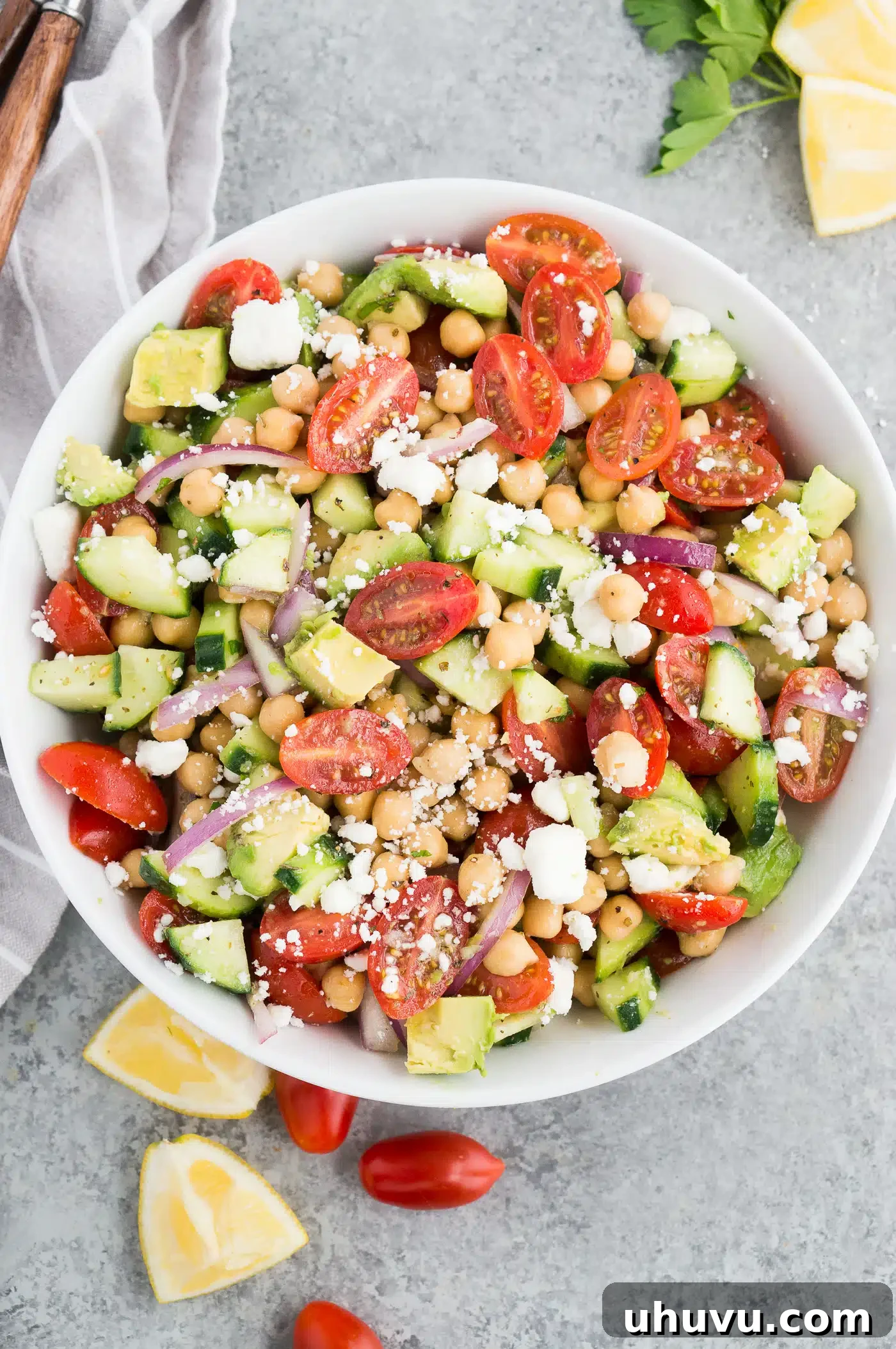 Garbanzo bean salad recipe with diced tomatoes and cucumbers in a white bowl, ready to serve.