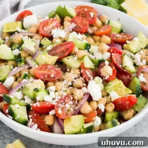 A serving of chickpea salad with avocado and other fresh ingredients in a white bowl.