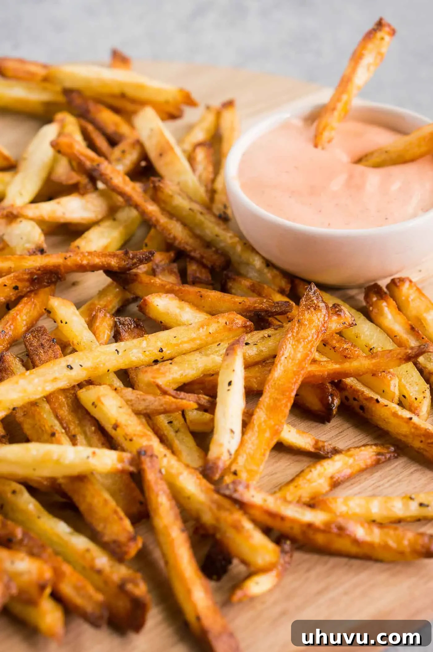Crispy oven-baked French fries served on a board with fry sauce for dipping