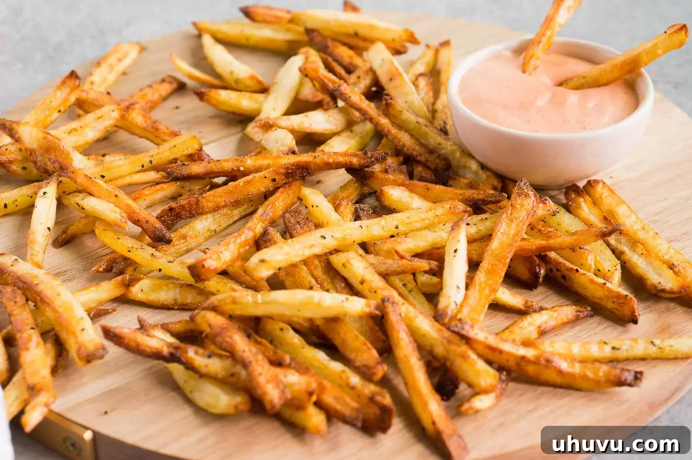 A close-up of oven-baked homemade French fries with a side of fry sauce