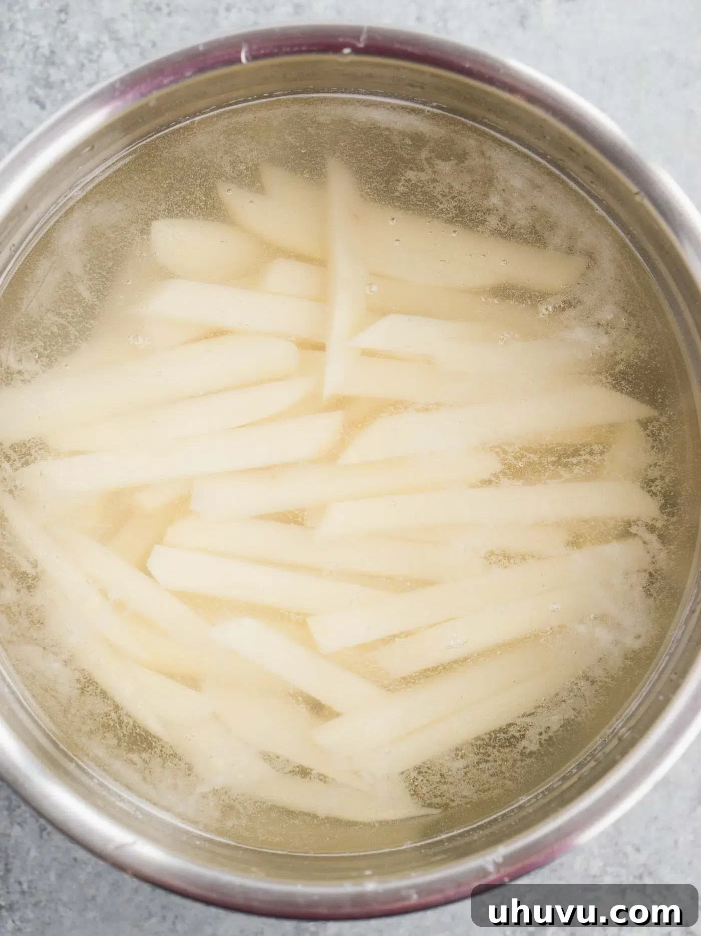 Potato fries soaking in a bowl of cold water