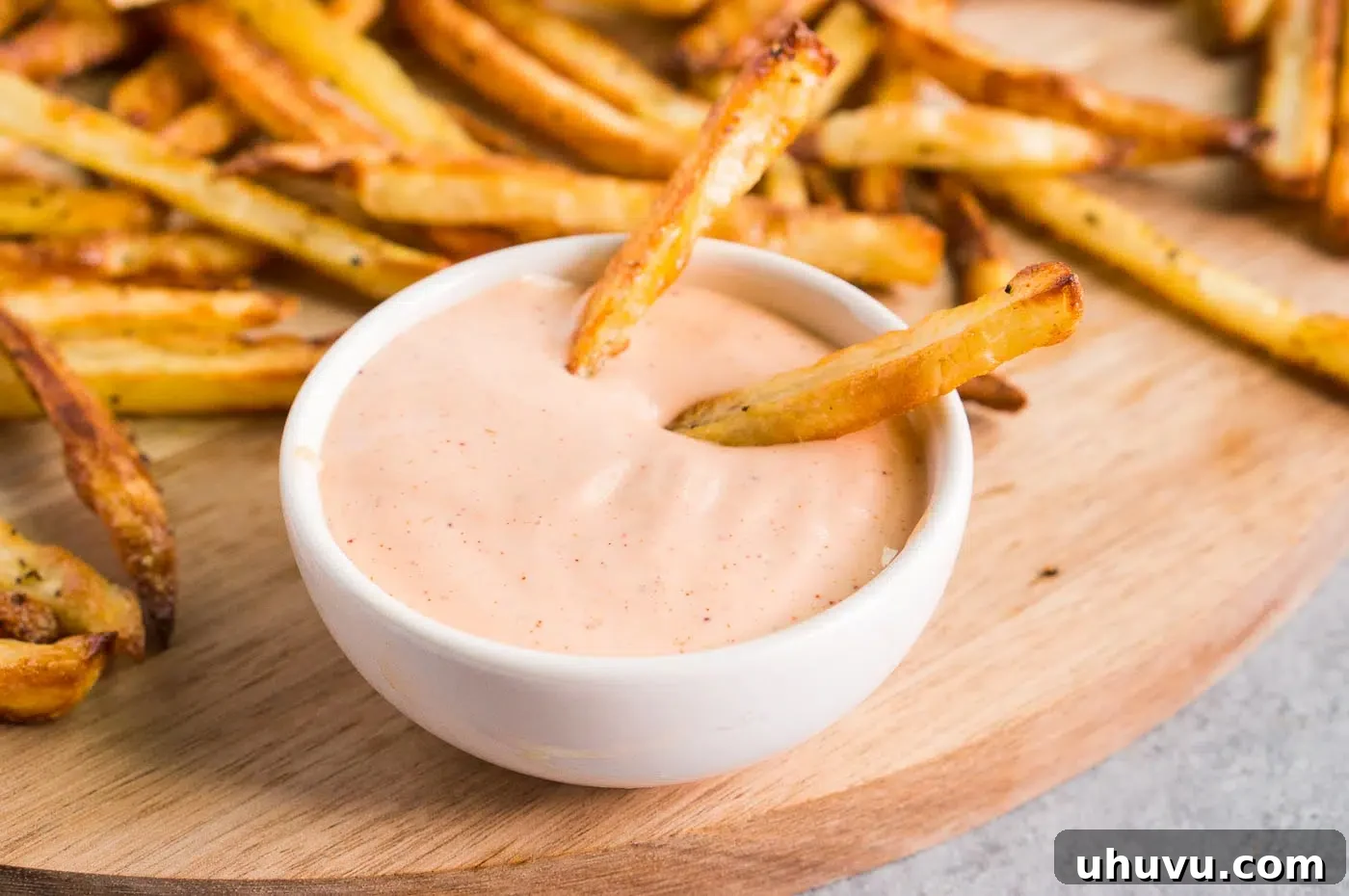 A beautifully presented bowl of creamy fry sauce, accompanied by a generous serving of crispy golden fries.