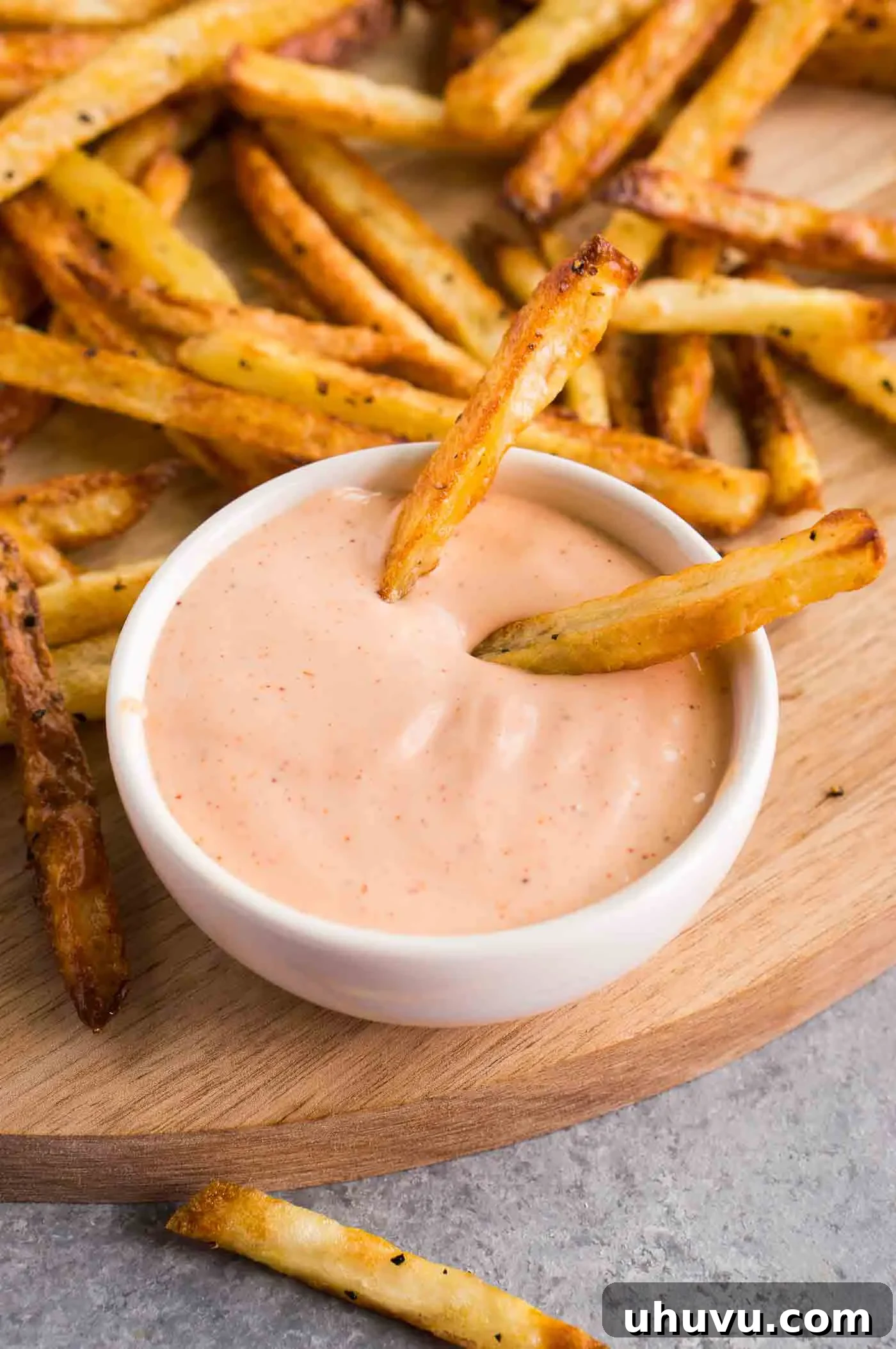 Crispy golden french fries gracefully dipped into a rich, creamy homemade fry sauce, showcasing its ideal consistency for dipping.