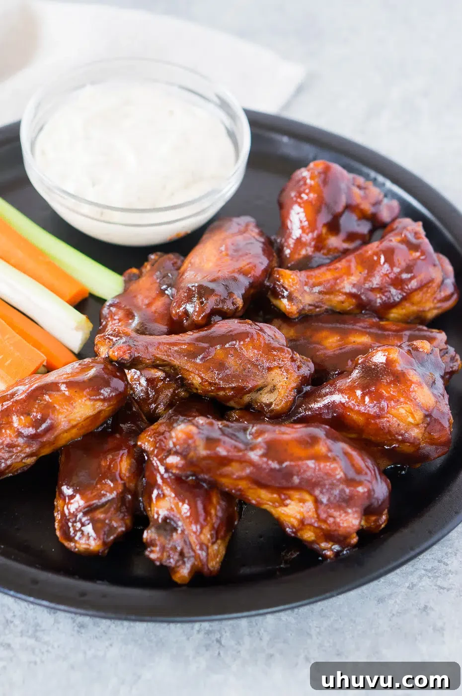 Platter of BBQ chicken wings with a side of ranch sauce and celery