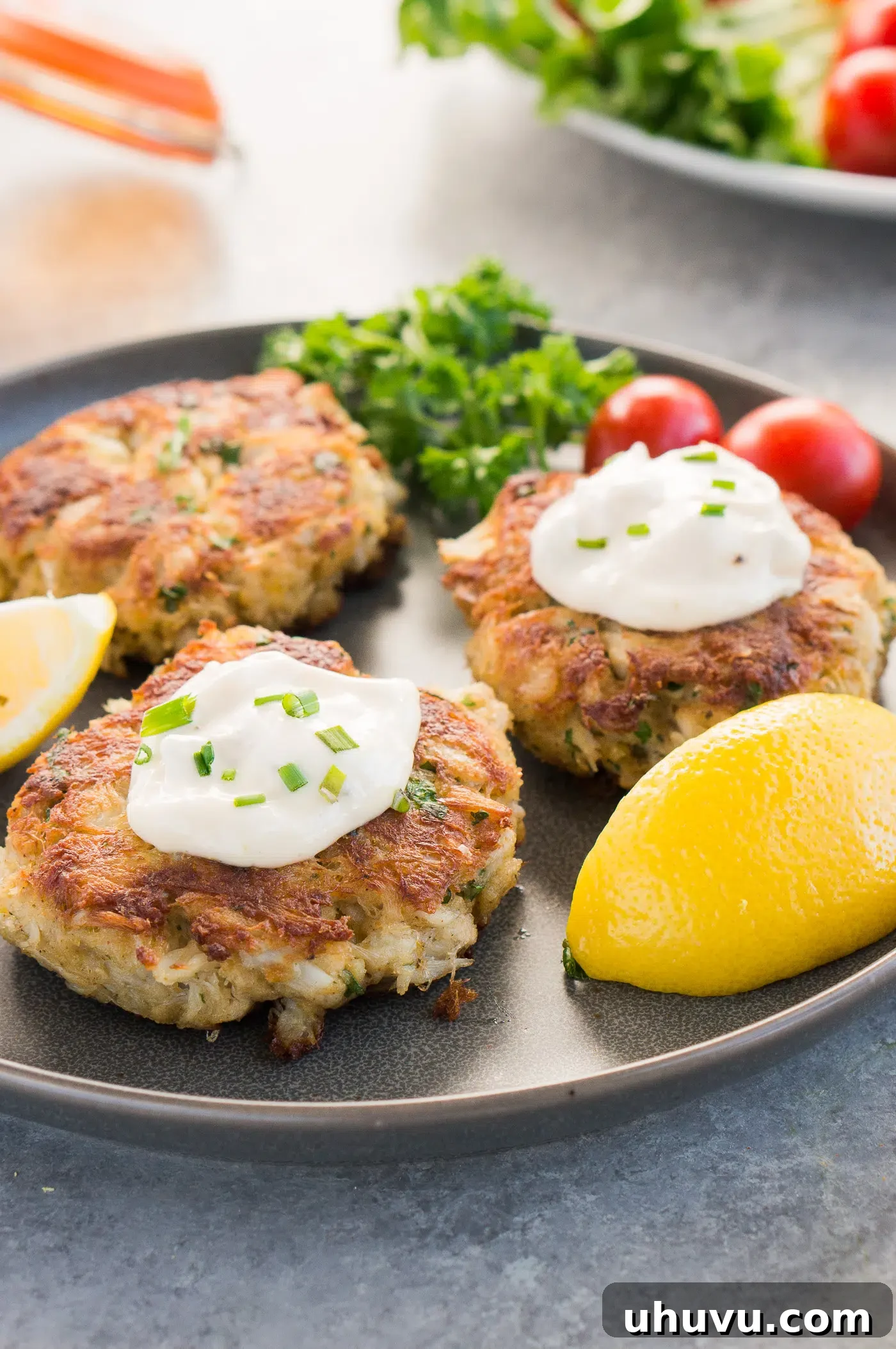 Golden Crab Delights 2 crab patties with tartar sauce on a plate