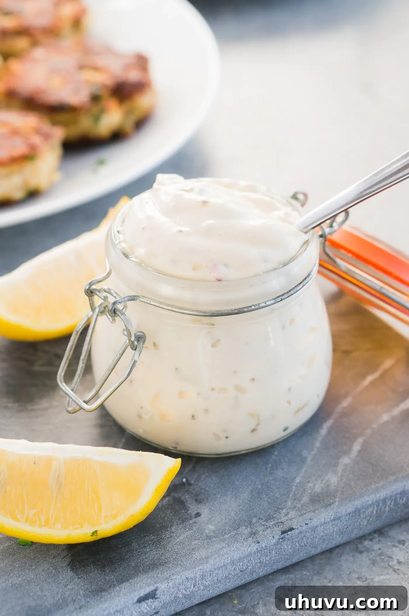 Freshly made tartar sauce in a small bowl on a wooden board, garnished with fresh herbs, ready to be served.