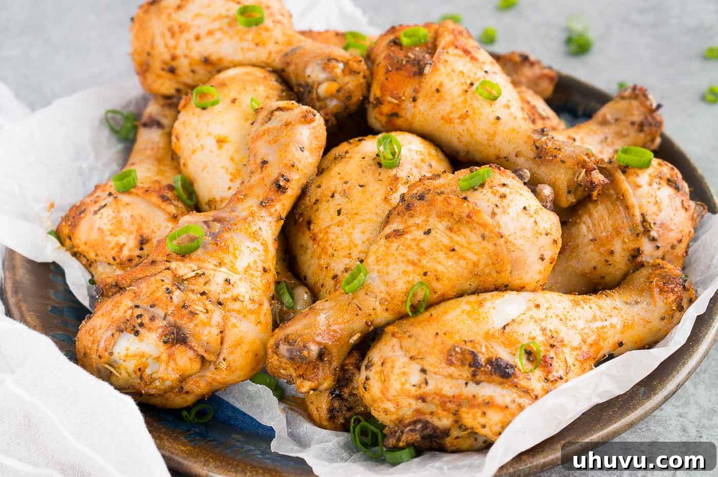Crispy Baked Chicken Drumsticks 3 Close up shot of several perfectly crispy baked chicken legs on a baking sheet, showcasing their golden-brown skin.