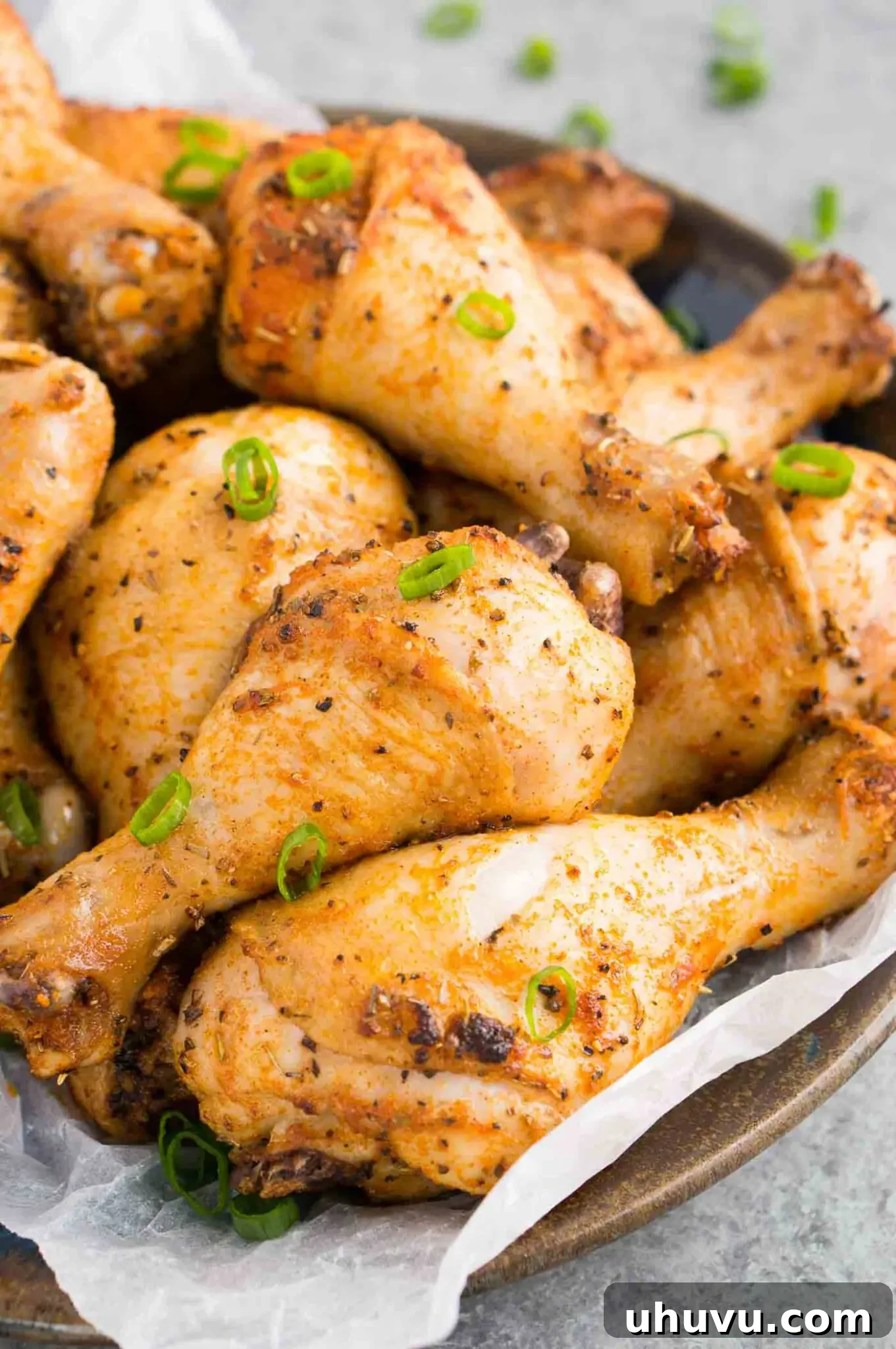 A plate filled with several oven baked chicken legs, garnished with fresh herbs, ready to be served.