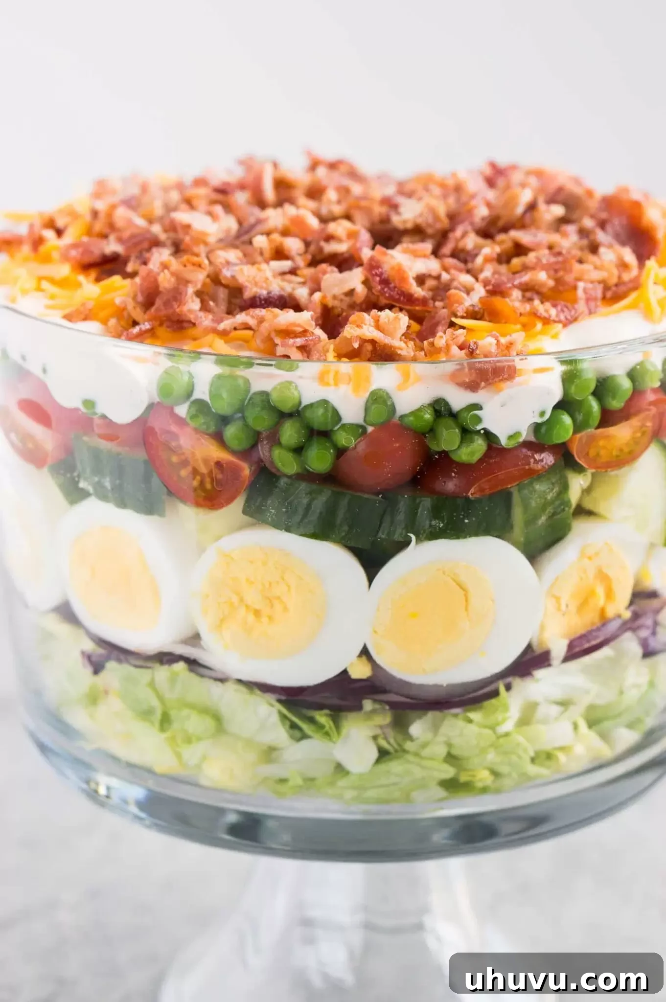 close up image of seven layer salad in a trifle dish