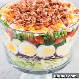 seven layer salad in a glass trifle dish